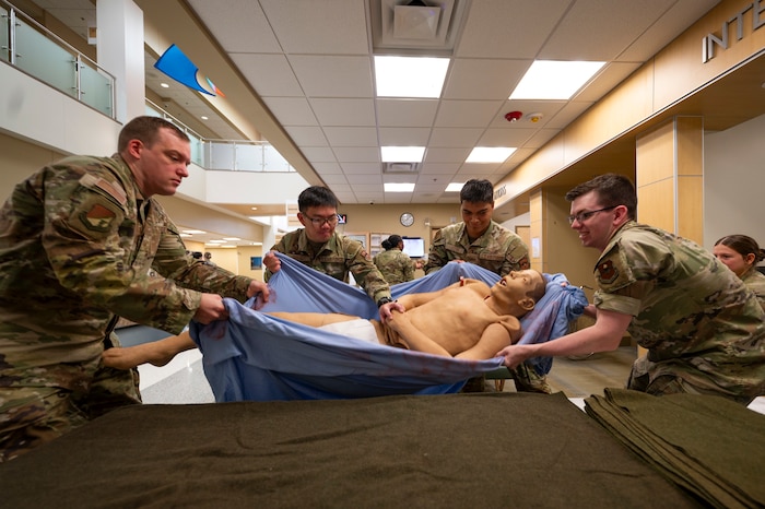 Airmen from the 49th Medical Group transfer a 200-pound training dummy from a gurney to an operating table during a Medic-X exercise at Holloman Air Force Base, New Mexico, July 16, 2025.