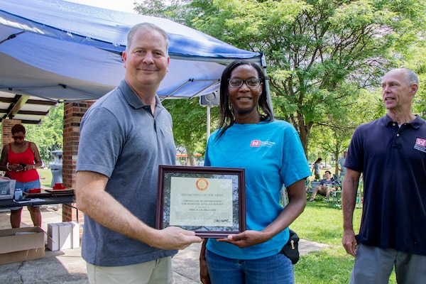 Women and man pose together holding an award certificate.