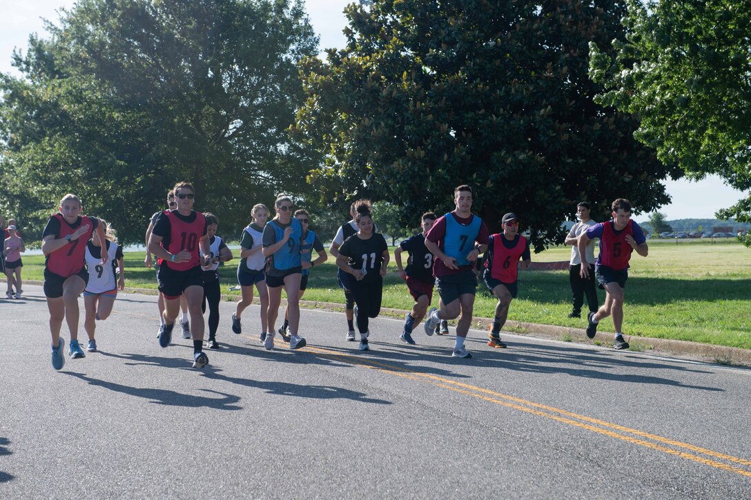 People running in a race on a road in a large group on a sunny day.