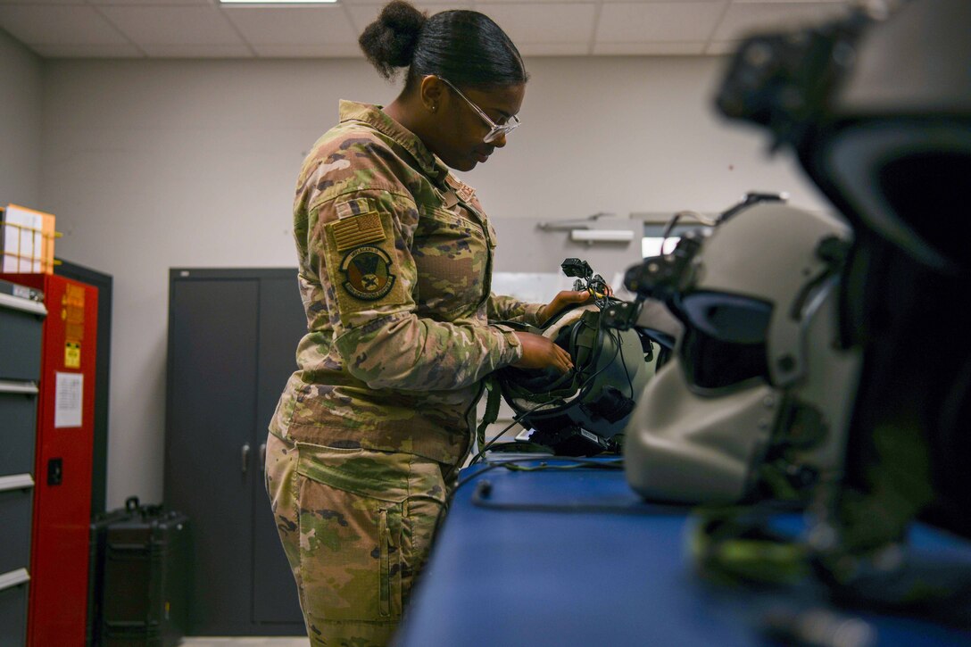 A service member inspects a flying helmet.