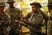 A Malaysian Army soldier demonstrates a traditional bamboo trap designed to catch small animals such as squirrels, highlighting indigenous survival techniques shared with Australian and U.S. Army partners during jungle training.