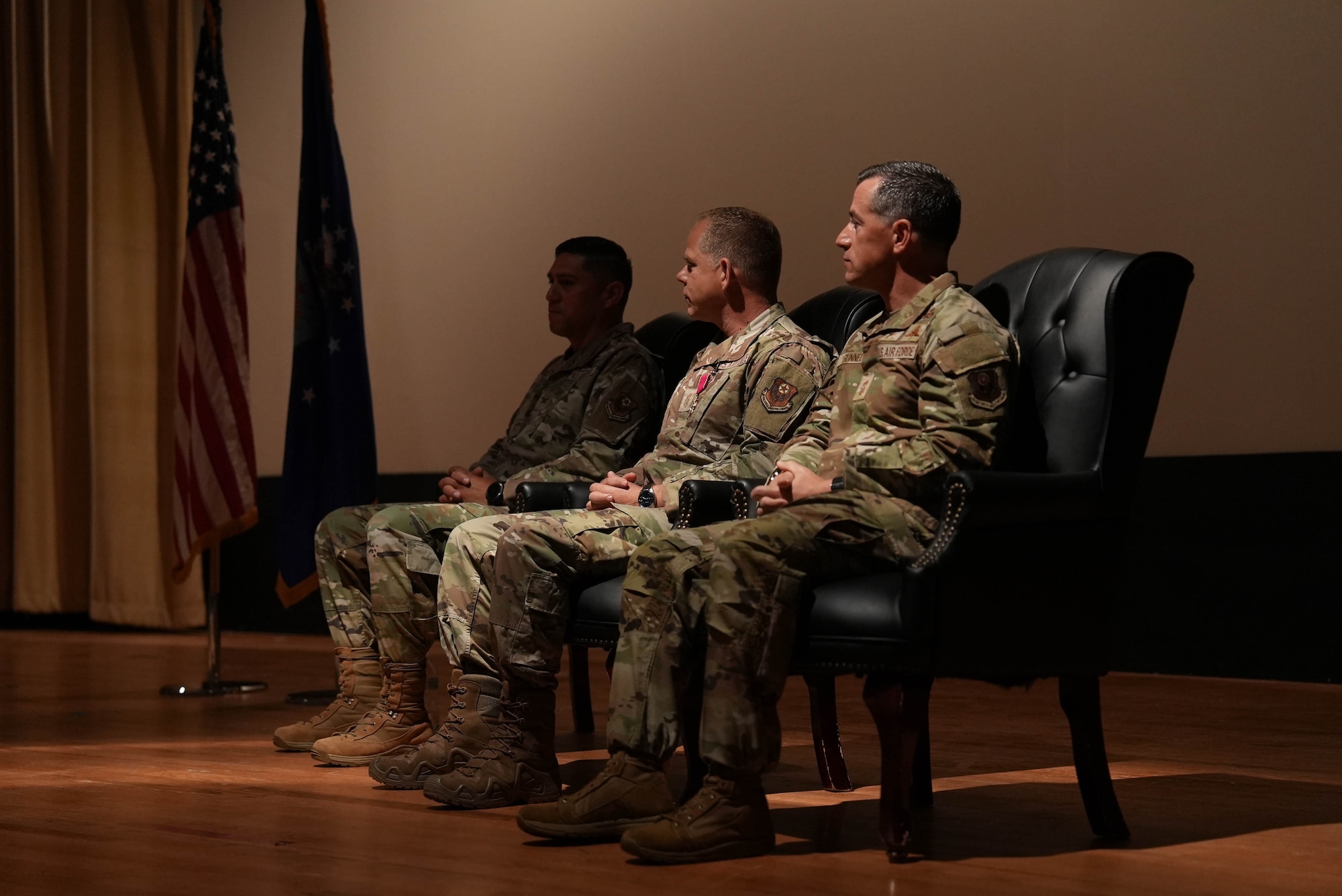 U.S. Air Force Col. Robert Johnston (left), 27th Special Operations Wing commander, U.S. Air Force Chief Master Sgt. Colin Fleck (center), outgoing 27th SOW command chief, and U.S. Air Force Chief Master Sgt. Thomas Gunnell (right), incoming 27th SOW command chief, sit together on stage during a change of responsibility ceremony at Cannon Air Force Base, New Mexico, July 21, 2025. Gunnell succeeds Fleck, who served as 27th SOW command chief from July 2023 to July 2025. (U.S. Air Force photo by Staff Sgt. Kevin Williams)