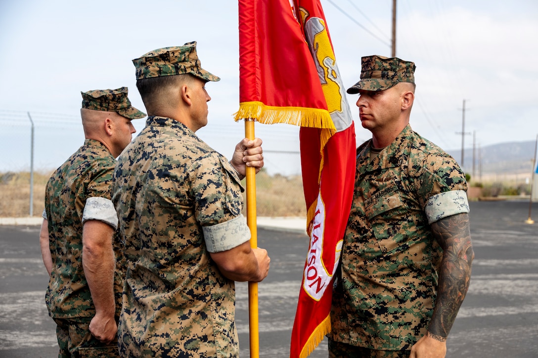 U.S. Marine Corps Sgt. Maj. William Mullen, right, sergeant major of 1st Air Naval Gunfire Liaison Company, I Marine Expeditionary Force Information Group, passes the organizational colors to Lt. Col. Thomas Giraldi, the outgoing commanding officer of 1st ANGLICO, during a change of command ceremony at Marine Corps Base Camp Pendleton, California, July 15, 2025. The ceremony commemorated the passing of command from Giraldi to Lt. Col. Jared Streeter. (U.S. Marine Corps photo by Lance Cpl. Gregory Hudson)