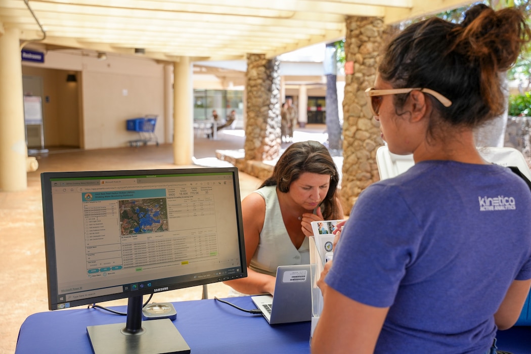A Navy Closure Task Force-Red Hill (NCTF-RH) community liaison officer shows home water testing results to a resident at a drinking water information booth at the Hickam Exchange on Joint Base Pearl Harbor-Hickam, Hawaii, July 10, 2025. Monthly events like this help inform residents about drinking water testing and where they can search for results online. Charged with the safe decommissioning of the Red Hill Bulk Fuel Storage Facility, NCTF-RH was established by the Department of the Navy as a commitment to the community and the environment. NCTF-RH continues to engage with the people of Hawaii, regulatory agencies, and other stakeholders as it safely and deliberately decommissions the facility. (U.S. Navy photo by Mass Communication Specialist 3rd Class Krystal Diaz)