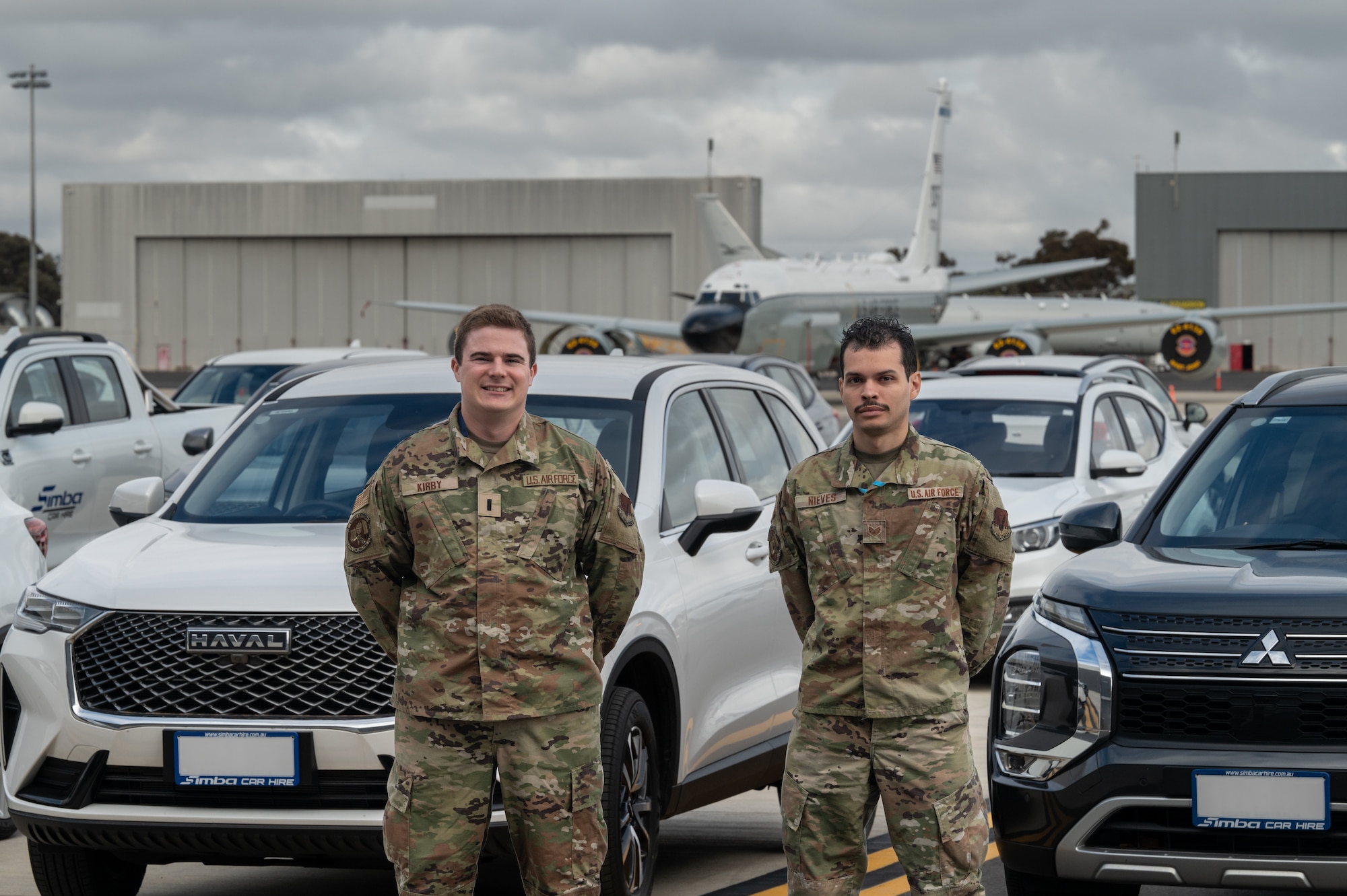 319th Contracting Squadron Airmen pose in front of vehicles they procured and an RC-135V/W Rivet Joint
