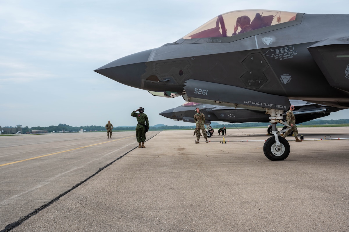 U.S. Marnie Private First Class Dylan Okwena, Marine Fighter Attack Squadron 225 powerline, plane captain (middle) salutes a U.S. Air Force pilot after marshalling the pilot during Sentry North exercise at Volk Field Air National Guard Base, Wisconsin, June 12, 2025. The exercise strengthened inter-service partnerships that are vital for integrated deterrence and global response.