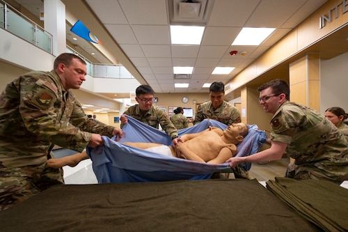 Airmen from the 49th Medical Group transfer a 200-pound training dummy from a gurney to an operating table during a Medic-X exercise at Holloman Air Force Base, New Mexico, July 16, 2025.