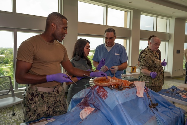 FORT LAUDERDALE, Fla. (July 12, 2025) Lt. Cmdr. Daniel Johnson, an orthopedic surgeon with Navy Medicine Readiness and Training Command Jacksonville, left, and Dr. Aeyal Oren, a general surgeon in private practice in Plantation, right, use a Tactical Combat Casualty Care Cut Suit to demonstrate emergency abdominal surgery to a participant during the “Top Doc” event at Nova Southeastern University’s Fort Lauderdale campus. Navy Medicine and Navy Recruiting Command partnered with NSU to launch “Top Doc”, a national initiative connecting local medical professionals, educators, and students while highlighting Navy Medicine’s capabilities and career opportunities. (U.S. Navy Photo by Mass Communication Specialist 1st Class Natalia Murillo)