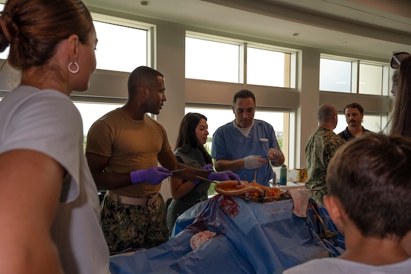 FORT LAUDERDALE, Fla. (July 12, 2025) Lt. Cmdr. Daniel Johnson, an orthopedic surgeon with Navy Medicine Readiness and Training Command Jacksonville, left, and Dr. Aeyal Oren, a general surgeon in private practice in Plantation, right, use a Tactical Combat Casualty Care Cut Suit to demonstrate emergency abdominal surgery during the “Top Doc” event at Nova Southeastern University’s Fort Lauderdale campus. Navy Medicine and Navy Recruiting Command partnered with NSU to launch “Top Doc”, a national initiative connecting local medical professionals, educators, and students while highlighting Navy Medicine’s capabilities and career opportunities. (U.S. Navy Photo by Mass Communication Specialist 1st Class Natalia Murillo)