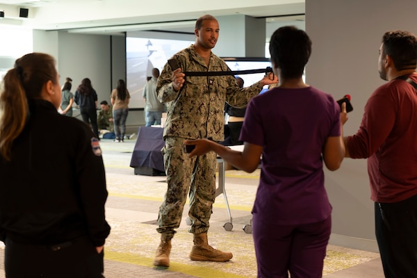 FORT LAUDERDALE, Fla. (July 12, 2025) Hospital Corpsman 2nd Class Jacob Munoz, assigned to Expeditionary Medical Facility 150-Mike, Navy Medicine Readiness and Training Command Jacksonville, demonstrates applying a tourniquet during the "Top Doc" event at Nova southeastern University's Fort Lauderdale campus. Navy Medicine and Navy Recruiting Command partnered with NSU to launch “Top Doc”, a national initiative connecting local medical professionals, educators, and students while highlighting Navy Medicine’s capabilities and career opportunities. (U.S. Navy Photo by Mass Communication Specialist 1st Class Natalia Murillo)