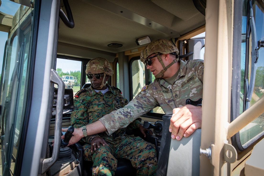 U.S. Army Staff Sgt. Logan Stevenson, a squad leader with the 130th Engineer Support Company, demonstrates the operations of  a High Mobility Engineer Excavator (HMEE) to an engineer officer of the Djibouti Armed Forces (DAF) at Camp Dodge, Iowa on May 15, 2024.