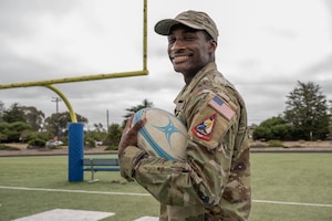 A Space Force solider poses with a rugby ball.