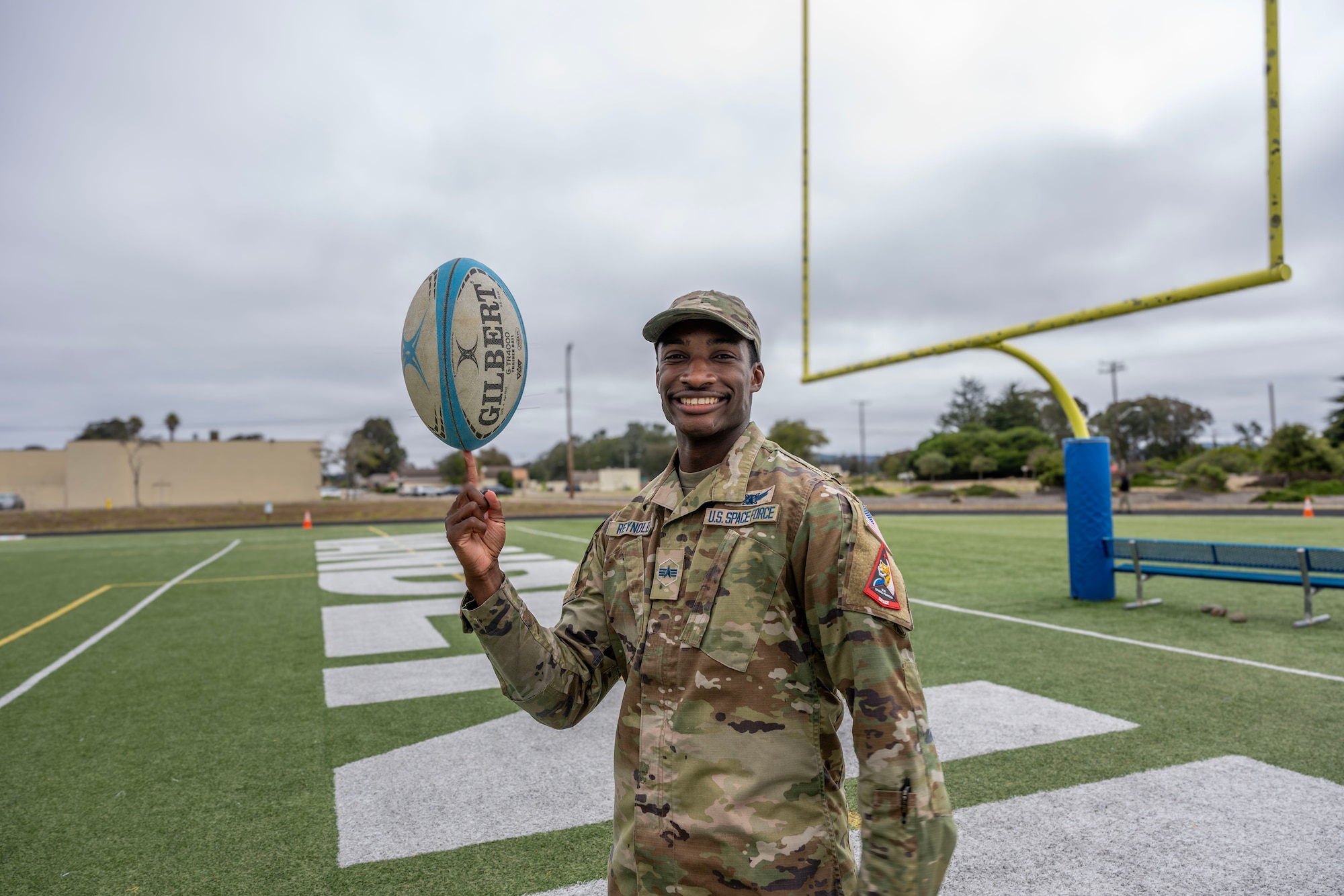 A Space Force solider poses with a rugby ball.