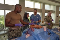 FORT LAUDERDALE, Fla. (July 12, 2025) Lt. Cmdr. Daniel Johnson, an orthopedic surgeon with Navy Medicine Readiness and Training Command Jacksonville, left, and Dr. Aeyal Oren, a general surgeon in private practice in Plantation, right, use a Tactical Combat Casualty Care Cut Suit to demonstrate emergency abdominal surgery to a participant during the “Top Doc” event at Nova Southeastern University’s Fort Lauderdale campus. Navy Medicine and Navy Recruiting Command partnered with NSU to launch “Top Doc”, a national initiative connecting local medical professionals, educators, and students while highlighting Navy Medicine’s capabilities and career opportunities. (U.S. Navy Photo by Mass Communication Specialist 1st Class Natalia Murillo)