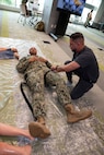 FORT LAUDERDALE, Fla. (July 12, 2025) Hospital Corpsman 2nd Class Jacob Munoz, assigned to Expeditionary Medical Facility 150-Mike, Navy Medicine Readiness and Training Command Jacksonville, guides a participant in applying a tourniquet during the "Top Doc" event at Nova Southeastern University's Fort Lauderdale campus. Navy Medicine and Navy Recruiting Command partnered  with NSU to launch “Top Doc”, a national initiative connecting local medical professionals, educators, and students while highlighting Navy Medicine’s capabilities and career opportunities. (U.S. Navy Photo by Mass Communication Specialist 1st Class Natalia Murillo)