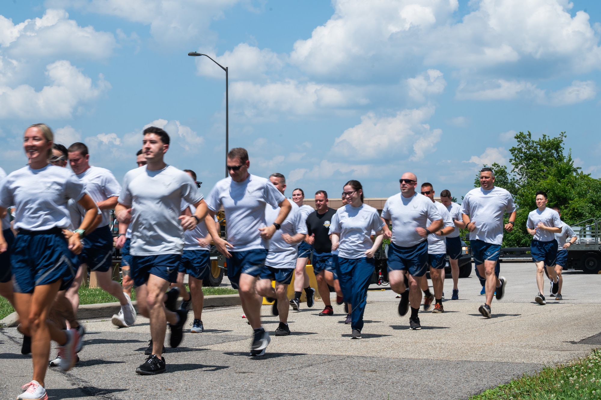 A group of Airmen in PT gear run down a road.