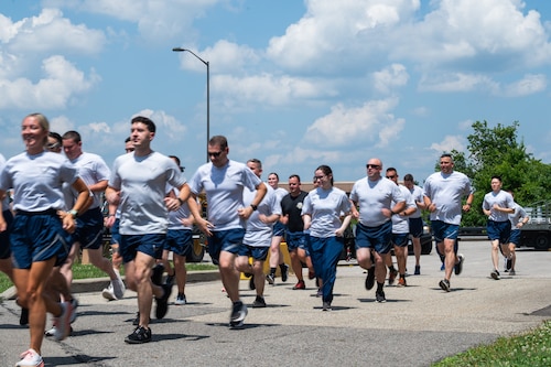 A group of Airmen in PT gear run down a road.