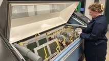 A team member operates a cyclic corrosion chamber as part of the corrosion prevention and control process.