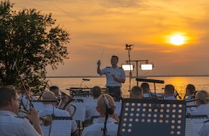 A man conducts the band sitting in front of him.
