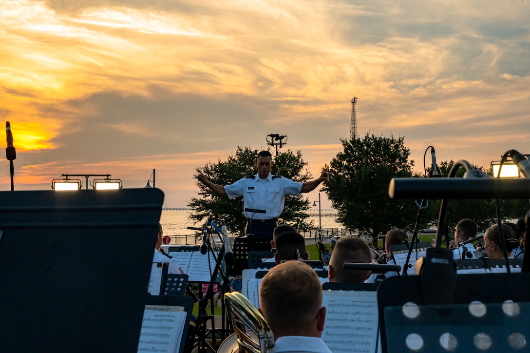 A man conducts the band sitting in front of him.