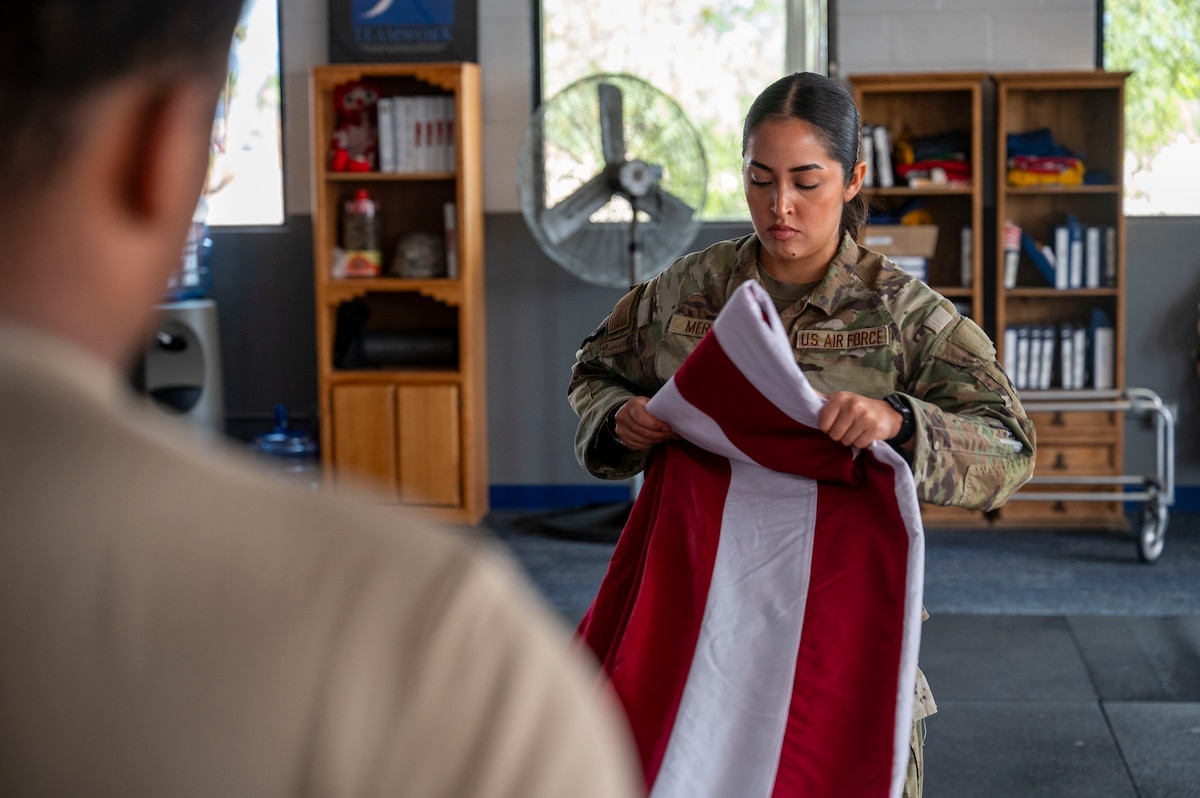 U.S. Air Force Senior Airman Melanie Mercado, an honor guardsman in training with the Davis-Monthan Air Force Base Honor Guard, practices the flag-folding technique at Davis-Monthan Air Force Base, Arizona, July 21, 2025. The precise folding of the flag is a key element in honor guard ceremonies, symbolizing respect and reverence during military funerals, retirements and other formal events. (U.S. Air Force photo by Airman Samantha Melecio)