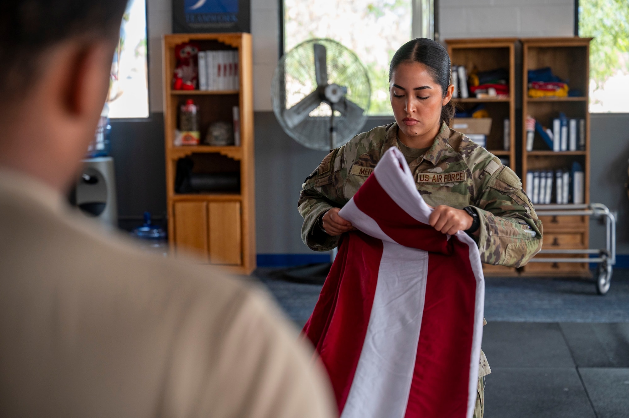 U.S. Air Force Senior Airman Melanie Mercado, an honor guardsman in training with the Davis-Monthan Air Force Base Honor Guard, practices the flag-folding technique at Davis-Monthan Air Force Base, Arizona, July 21, 2025. The precise folding of the flag is a key element in honor guard ceremonies, symbolizing respect and reverence during military funerals, retirements and other formal events. (U.S. Air Force photo by Airman Samantha Melecio)