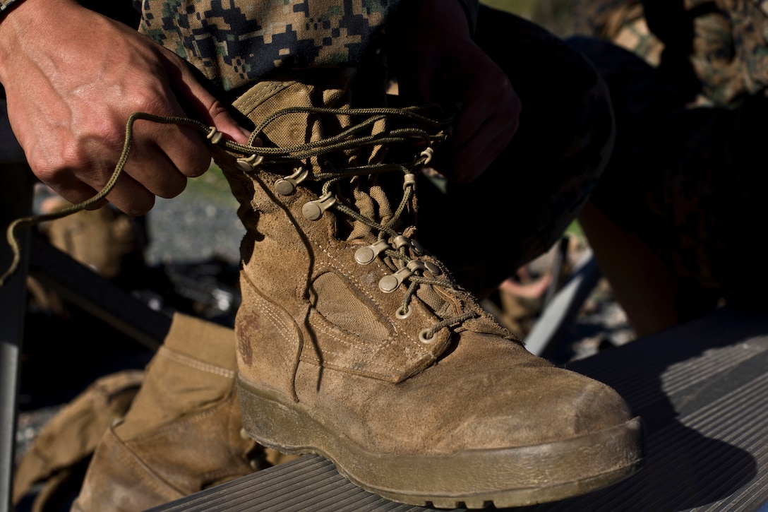 U.S. Marine Corps Cpl. Eduardo Meza, with the Installation Personnel Administration Center, Headquarters Company, Headquarters and Service Battalion, removes his boot during a health inspection after a super squad competition hike at Eastern Miramar Marine Corps Air Station Miramar, California.