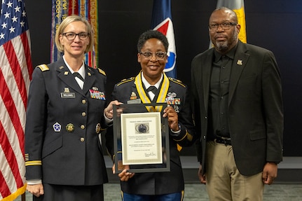 Col. Michelle M. Williams, U.S. Army Financial Management Command commander, left, and Retired Command Sgt. Maj. Gennaro Penn, U.S. Army Finance Corps Association president, right, present Master Sgt. Candace M. Davis, USAFMCOM Operational Support Team senior financial management systems instructor, with a Maj. Gen. Nathan Towson Regimental Medallion at the Maj. Gen. Emmett J. Bean Federal Center April 11, 2025. A native of Augusta, Georgia, Davis enlisted in the Army as a financial management specialist in October 2002. (U.S. Army photo by Mark R. W. Orders-Woempner)