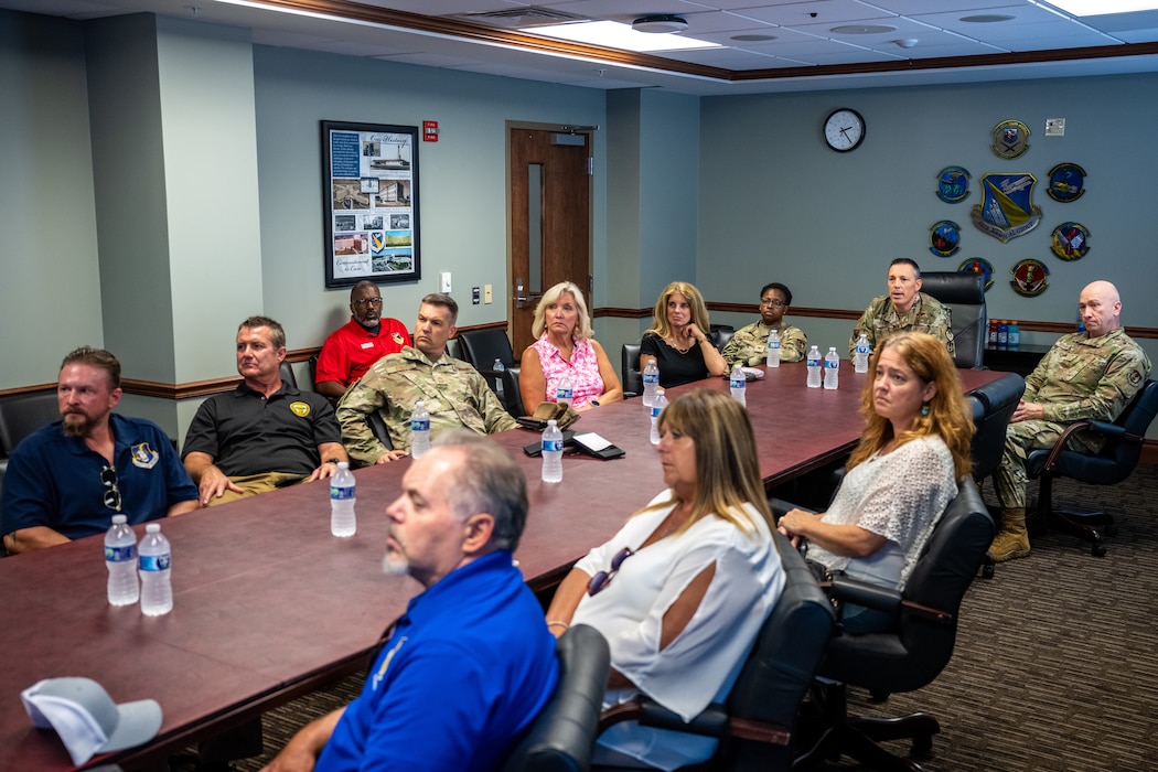 A large group of people, both military and civilian, sit around a large conference table