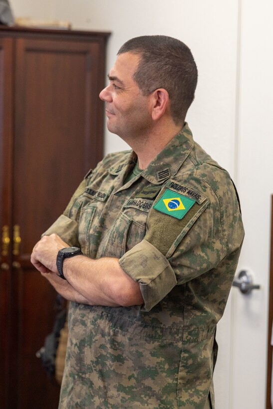Capitão de mar e guerra (Brazilian colonel) Alexandre Soares de Arajo listens to a welcome brief before observing Service Level Training Exercise 4-25, Marine Corps Air Ground Combat Center, Twentynine Palms, California, July 14, 2025. Arajo is a part of a delegation that visited MCAGCC to observe the SLTE process, designed, enabled, and overseen by the Tactical Training and Exercise Control Group, in order to improve their own standard operating procedures and increase operability with their U.S. partners. (U.S. Marine Corps photo by Lance Cpl. Jozef Majewski)