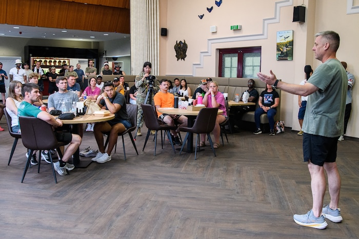 A man with a microphone speaks to a room full of people
