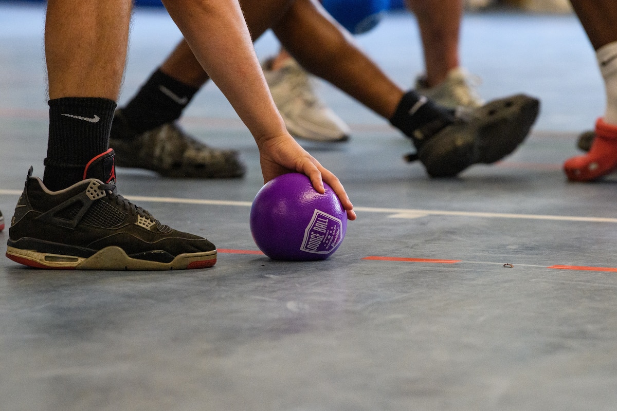 A hand picks up a dodgeball.