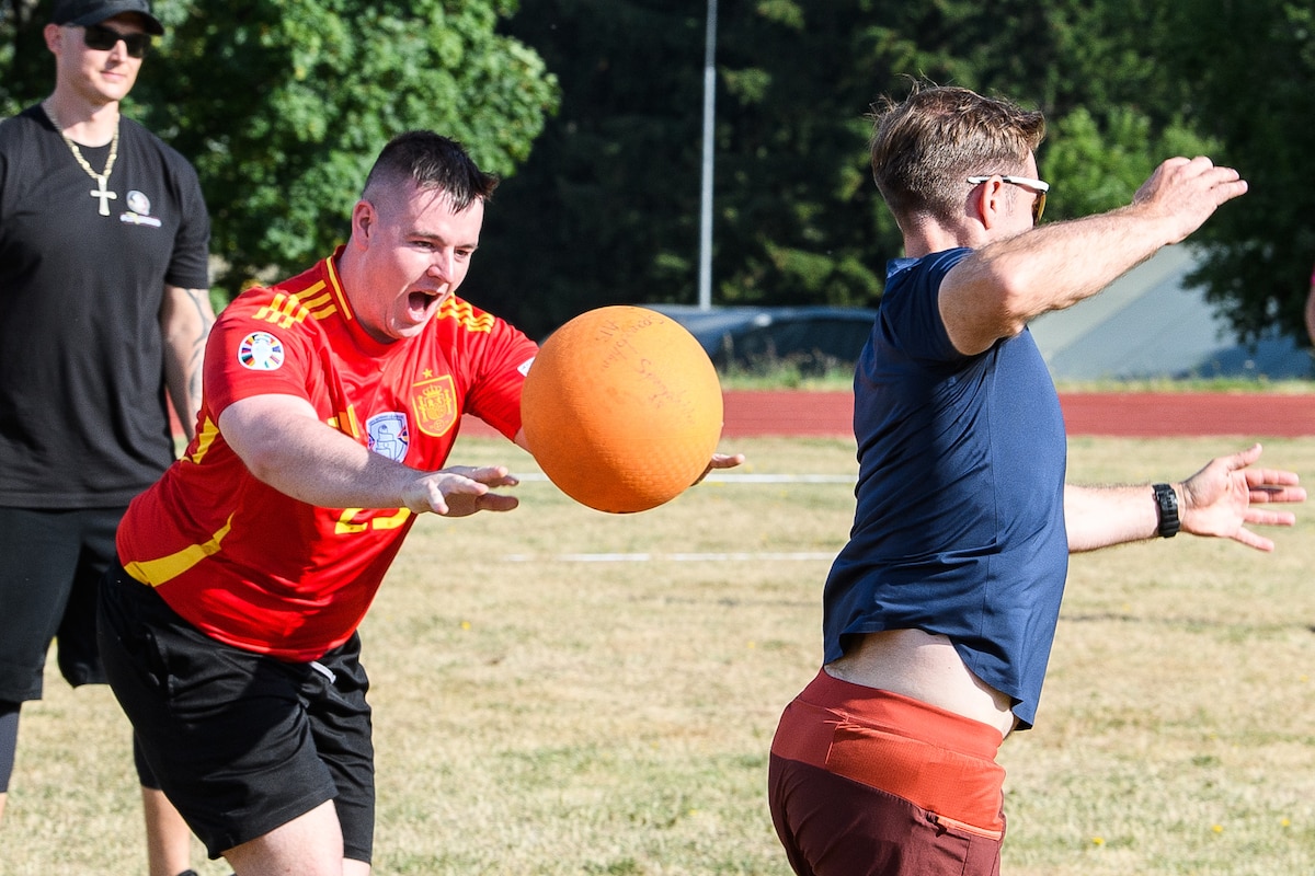 A man throws a kickball at another man.