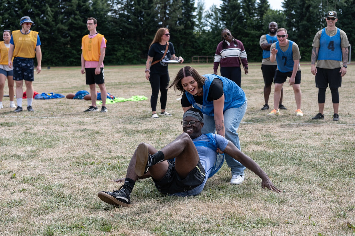 A woman laughs as she pulls a laughing man across a field.