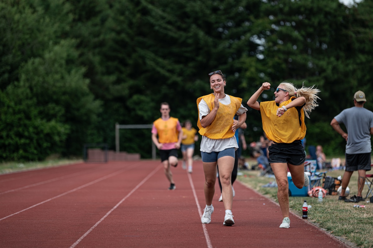 A woman cheers for another woman walking in a track.