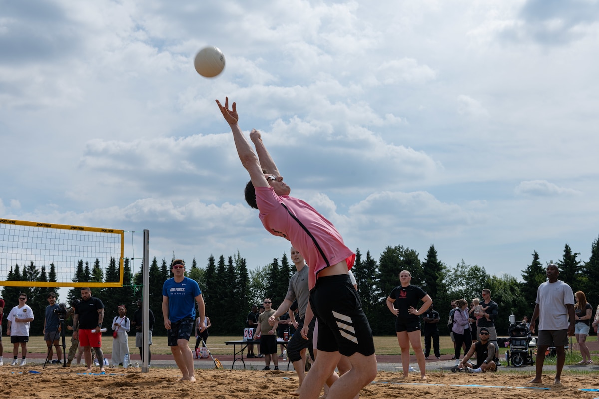 A man jumps toward a volleyball in front of a crowd.