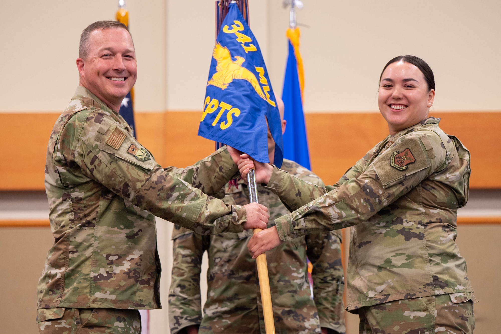 Uniformed personnel hold a flag.