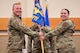 Uniformed personnel hold a flag.