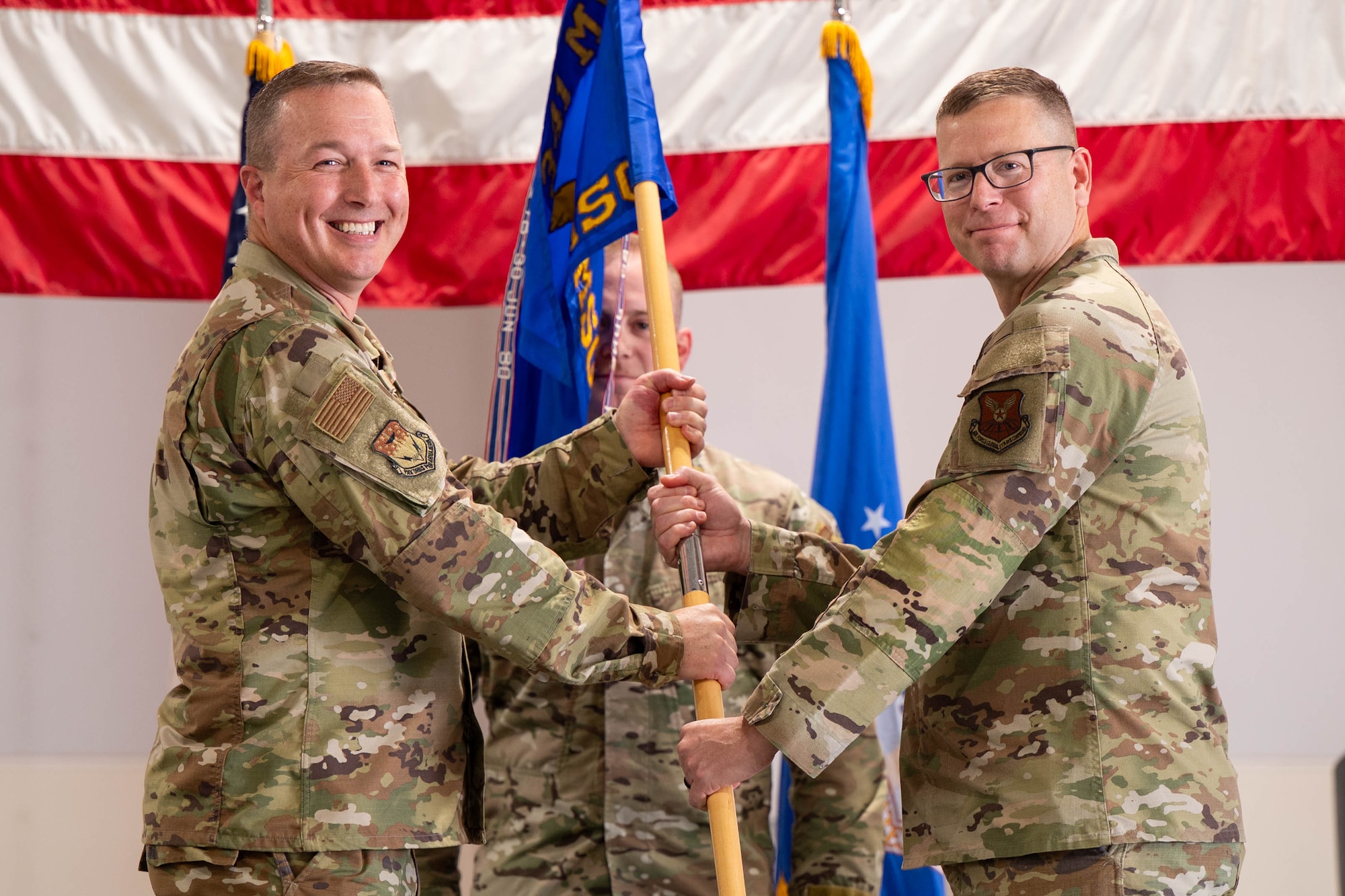 Men in uniform hold a flag.