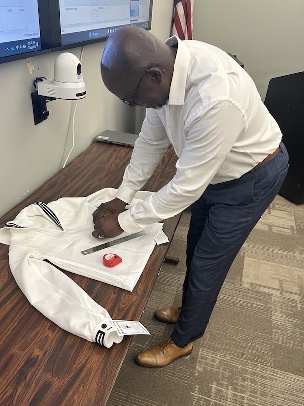 a man adjusts a uniform jumper on a table