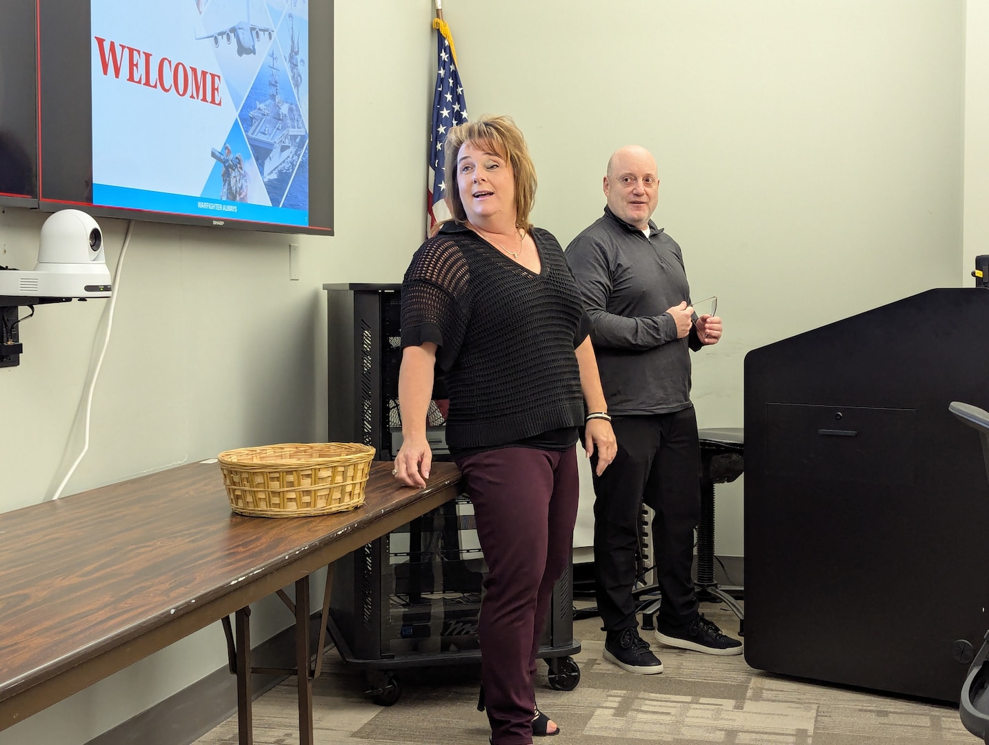 a man and woman stand next to podium and presentation screen
