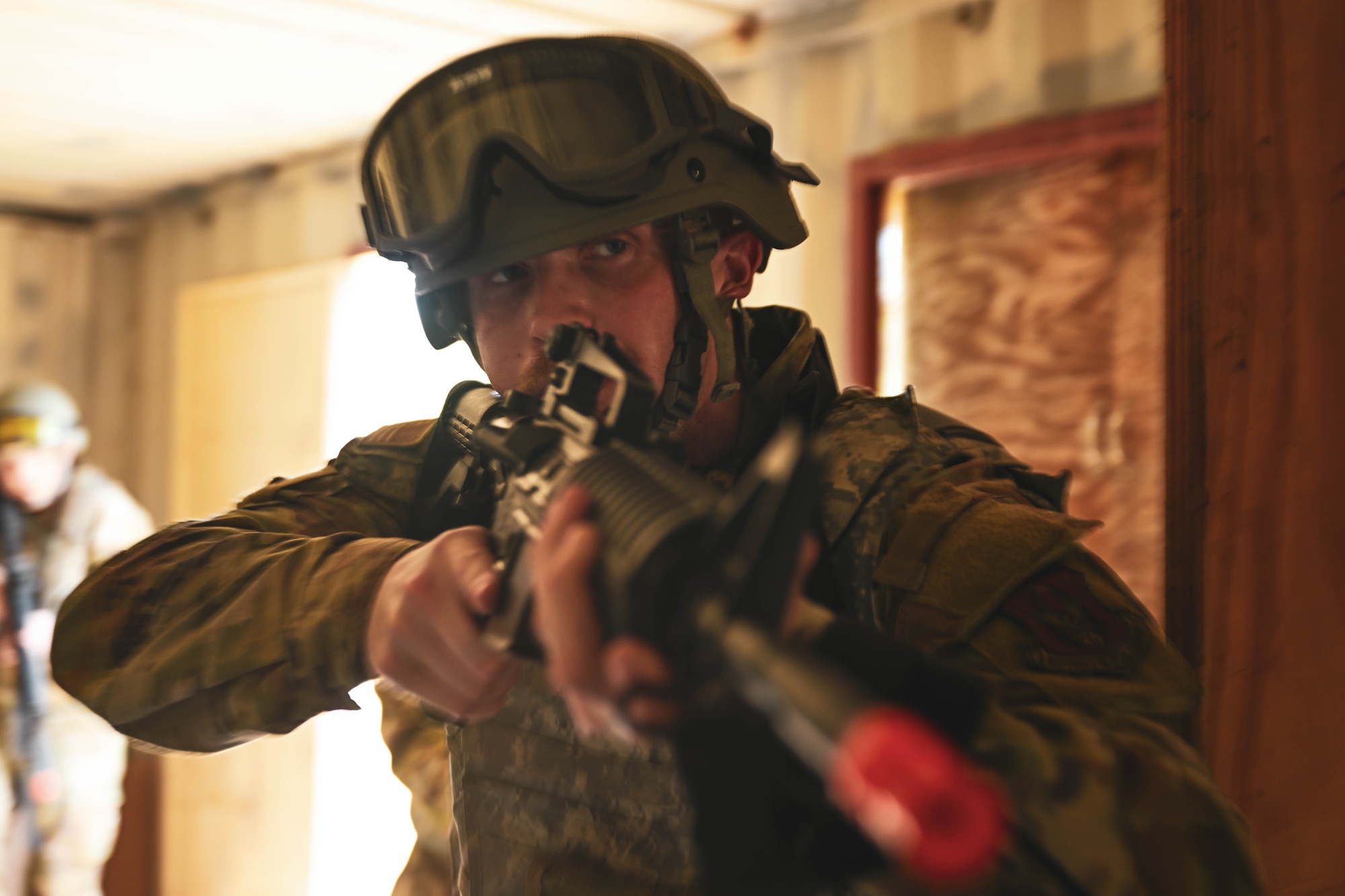 A man holding a rifle charges through a doorway.