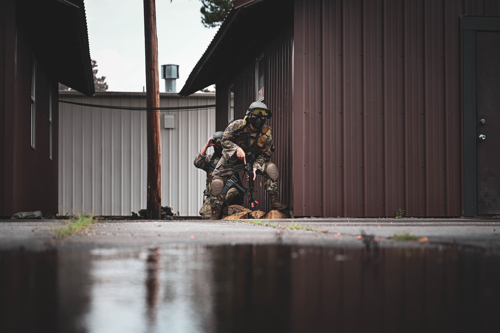 A group of people in uniform crouch with weapons.