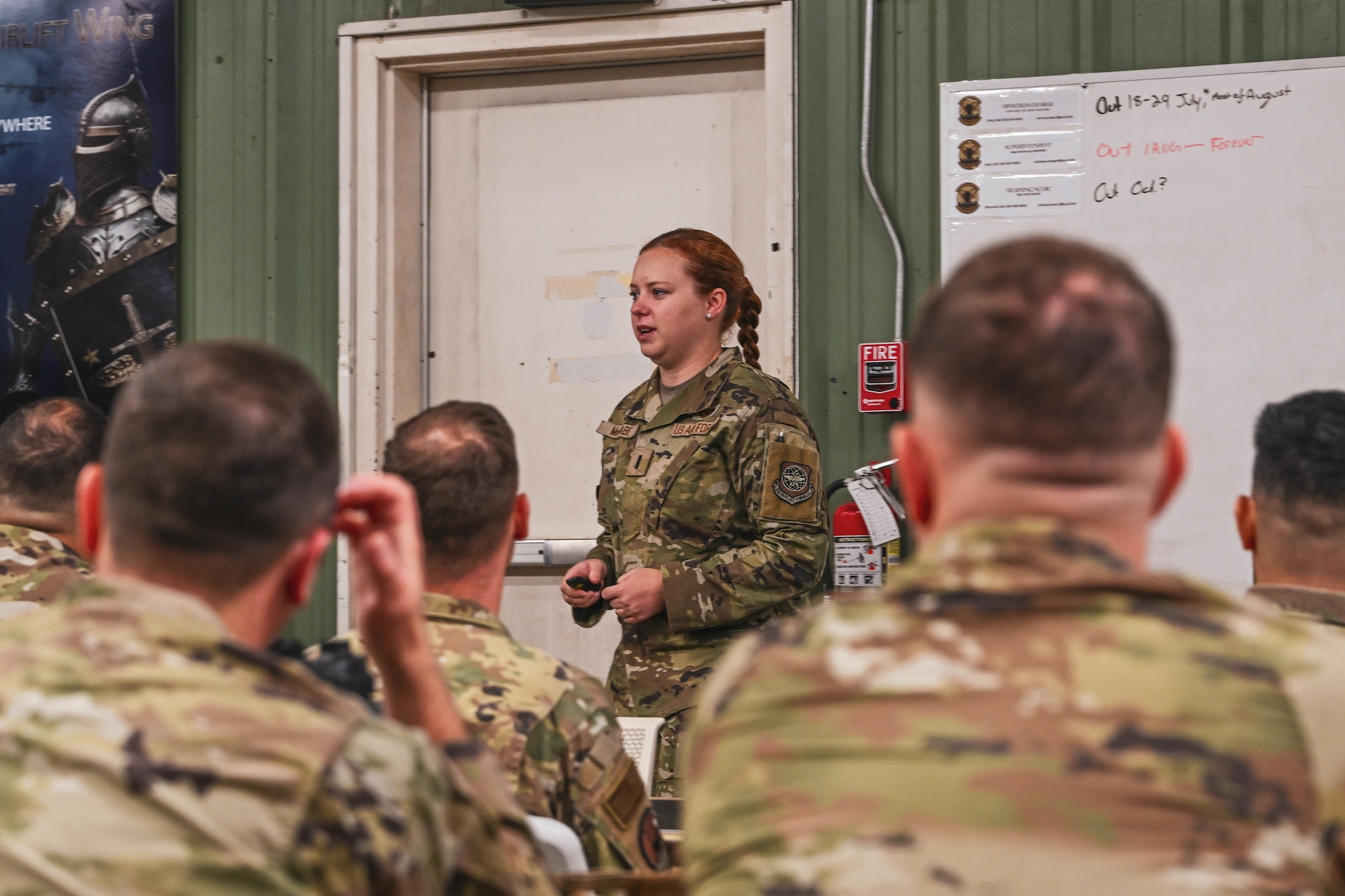 A woman in uniform speaks to other people in uniform in a classroom.
