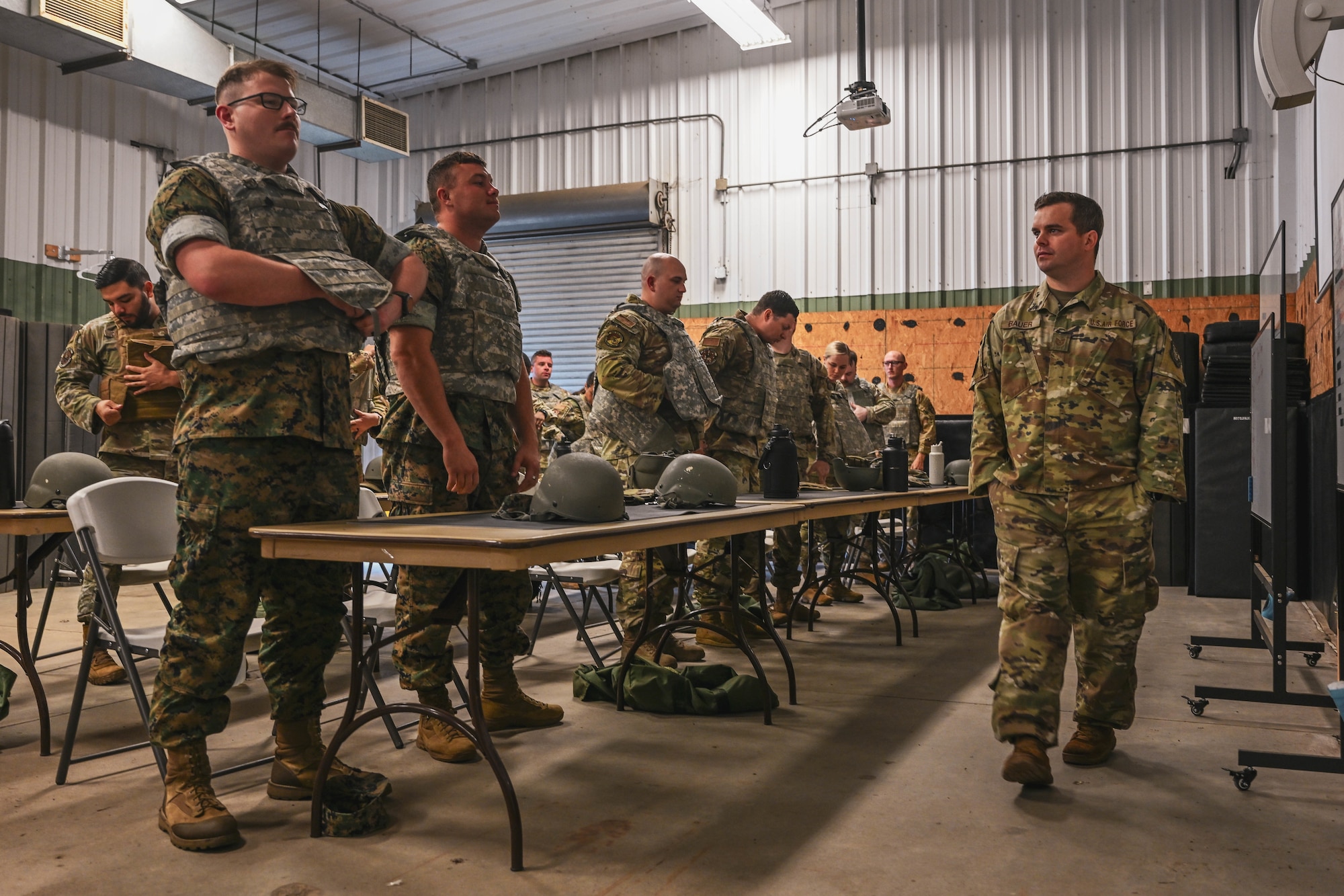 A group of people in uniform try on combat vests.