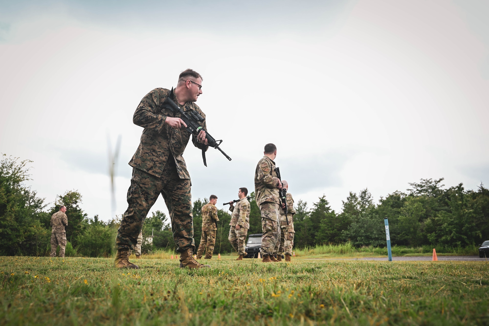 A group of men in uniform hold firearms in a circle.