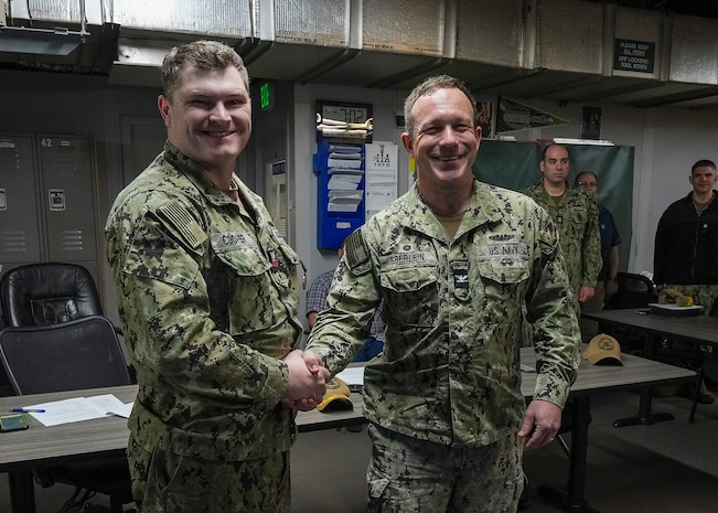 Hull Maintenance Technician 1st Class Noah Cooper and Capt. Michael Eberlein, commanding officer, TRFB, pose for a photo at TRFB.