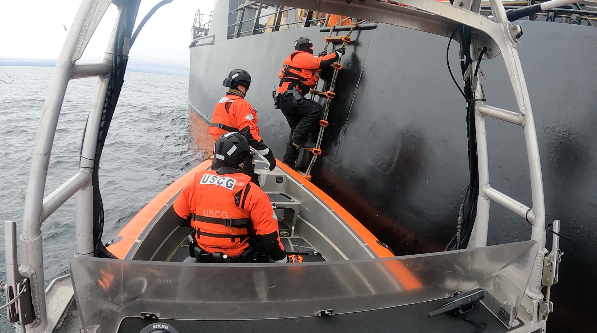 Petty Officer 3rd Class John Meehan (right), a U.S. Coast Guard boarding officer, embarks a fishing vessel via a Jacob’s Ladder to conduct a boarding while the U.S. Coast Guard Cutter Munro (WMSL 755) patrols the Bering Sea May 22, 2025. Munro’s crew conducted a total of 32 boardings in the Bering Sea to preserve fisheries’ resources and ensure each vessel’s safety, survival, and communications gear complied with federal regulations. (U.S. Coast Guard photo by Petty Officer 3rd Class Lucas Ritch.)