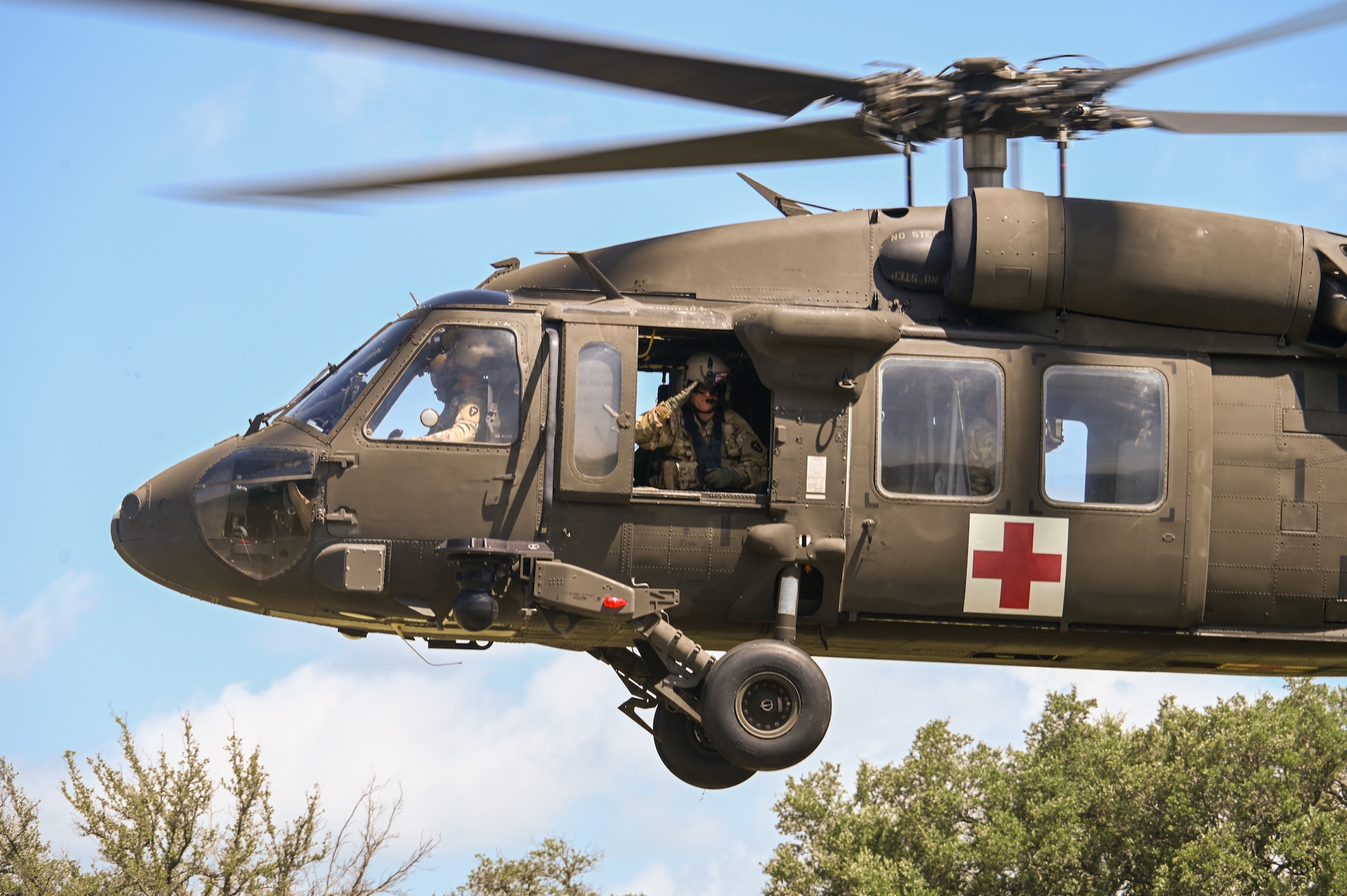 Texas Army National Guard Lt. Col. Christopher Stephens, UH-60 flight surgeon with Charlie Company, 2nd General Support Aviation Battalion, 36th Combat Aviation Brigade, salutes U.S. Air Force personnel and others during takeoff at OPERATION DUSTOFF VIGILANCE ’25 at Joint Base San Antonio-Camp Bullis, Texas, July 16, 2025.