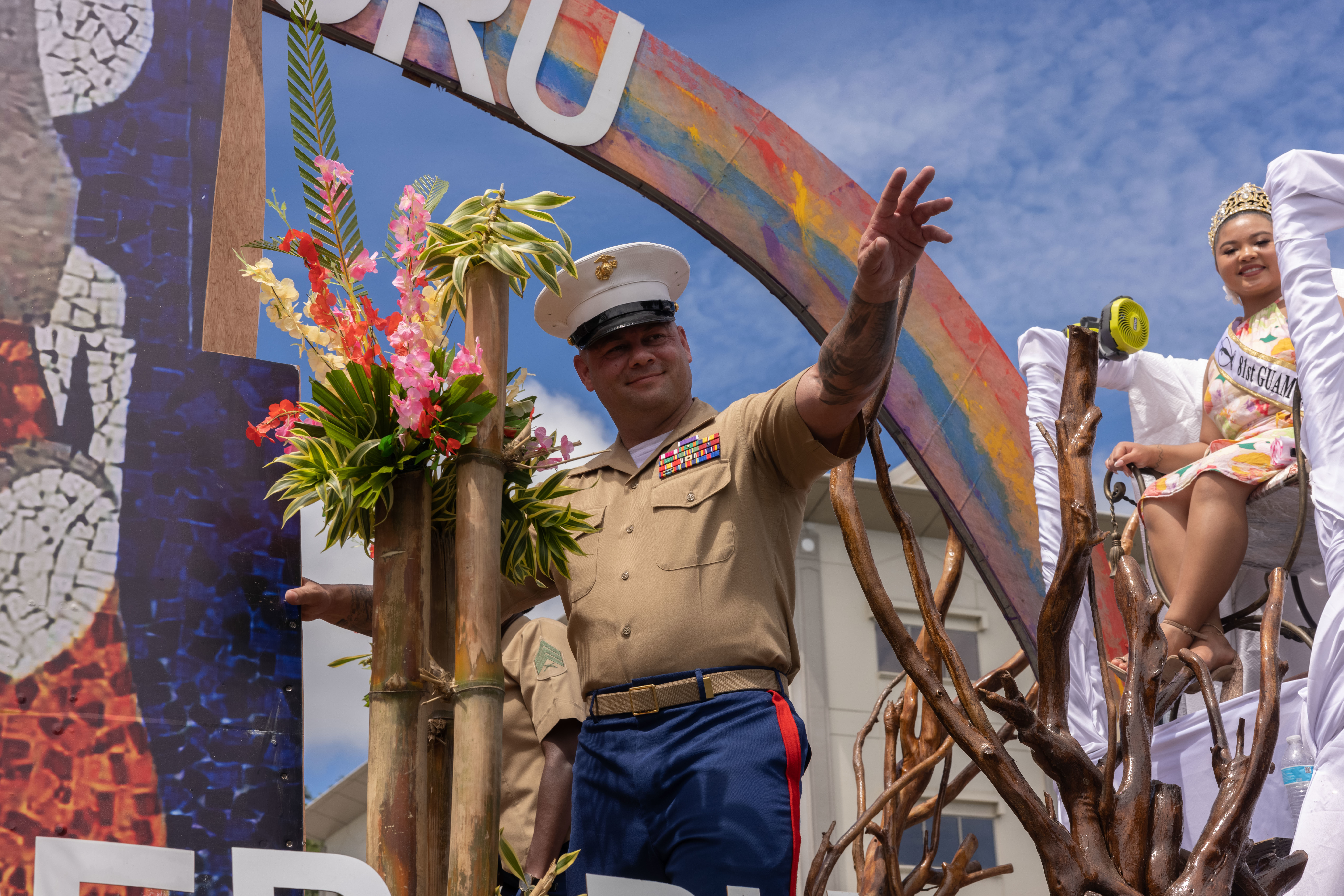 U.S. Marine Corps Master Sgt. Bruce Miller, communications chief, Headquarters Company, Marine Corps Base Camp Blaz, and Float riders on the Village of Manenggon float, wave to the crowd during the 81st Guam Liberation Day parade in Hagåtña, Guam, July 21, 2025. The parade is a celebration of U.S. forces liberating Guam from Imperial Japanese Forces in 1944 during World War II. Throughout the month of July there are several events and ceremonies held as part of Guam’s Liberation Month. (U.S. Marine Corps photo by Lance Cpl. Tanner Currin)
